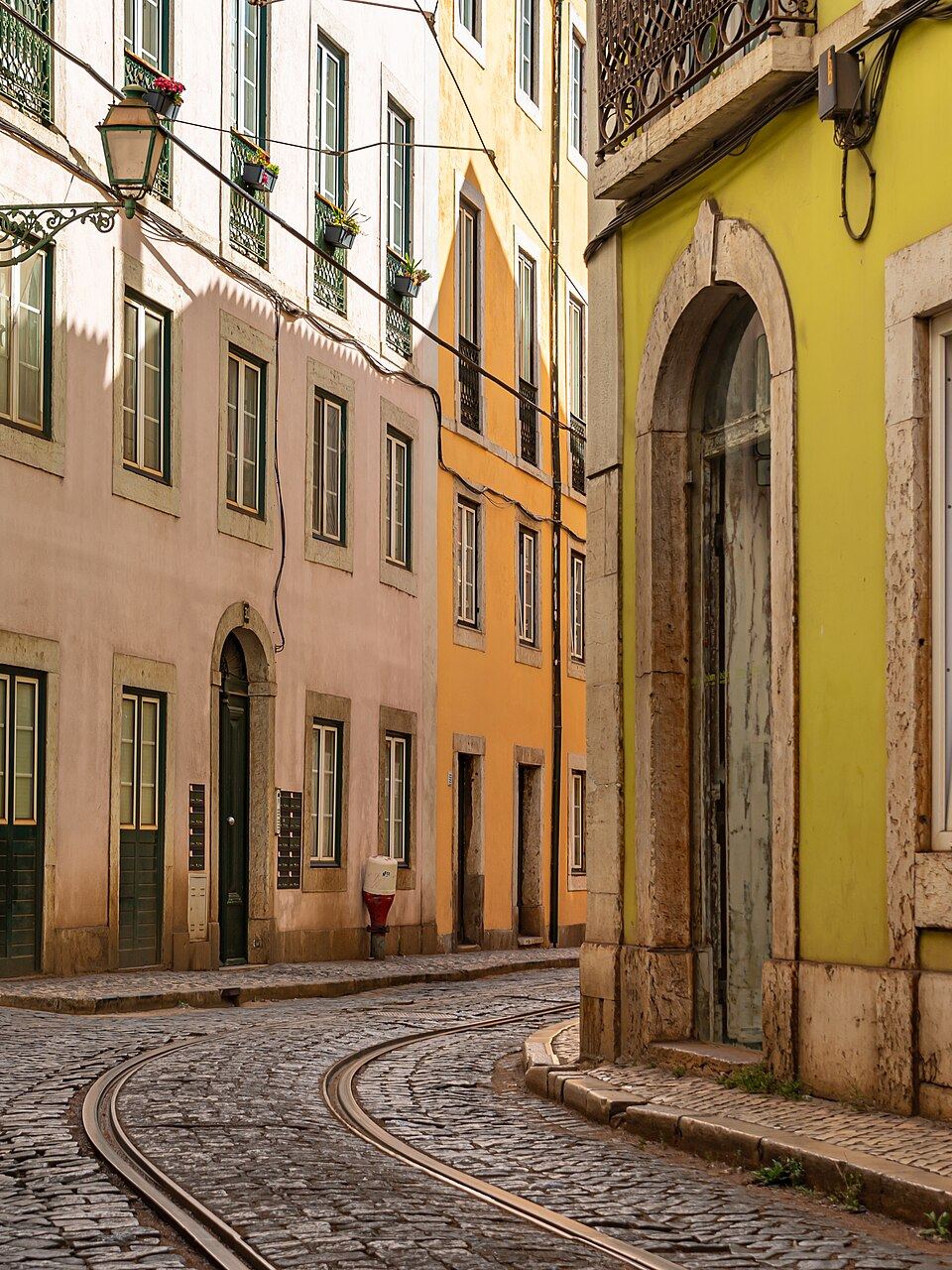 Eine gepflasterte Gasse mit Straßenbahnschienen in Alfama