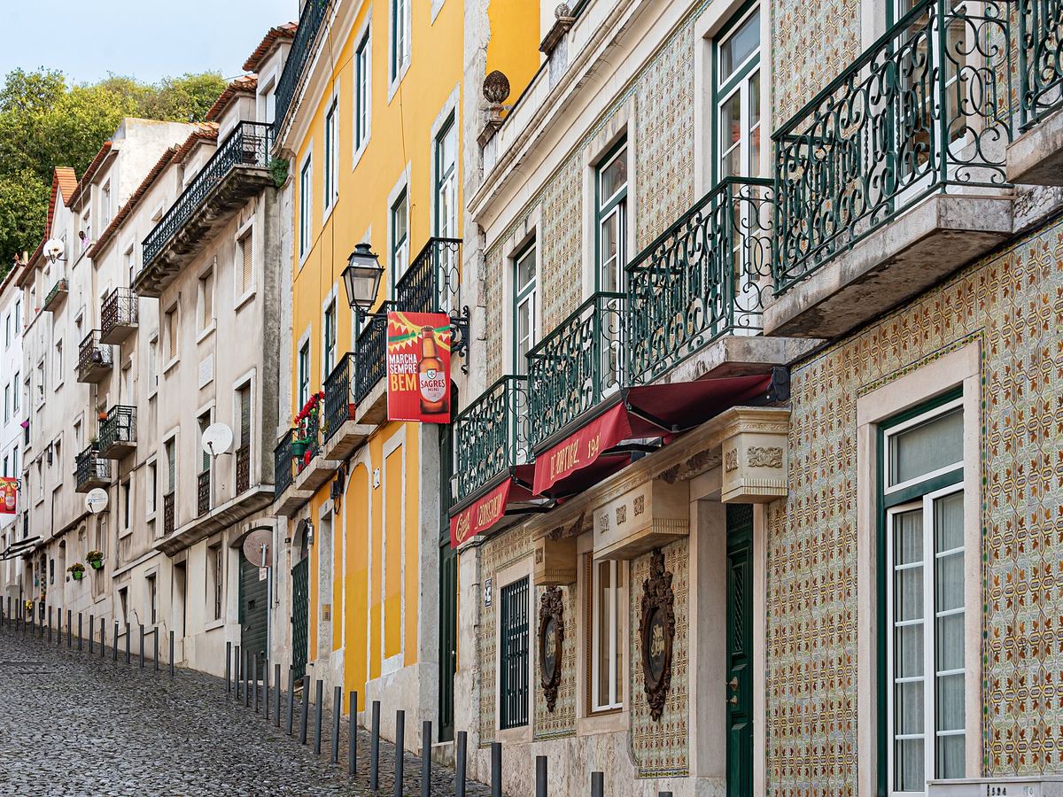 Eine geflieste Straße in Alfama mit schmiedeeisernen Balkonen